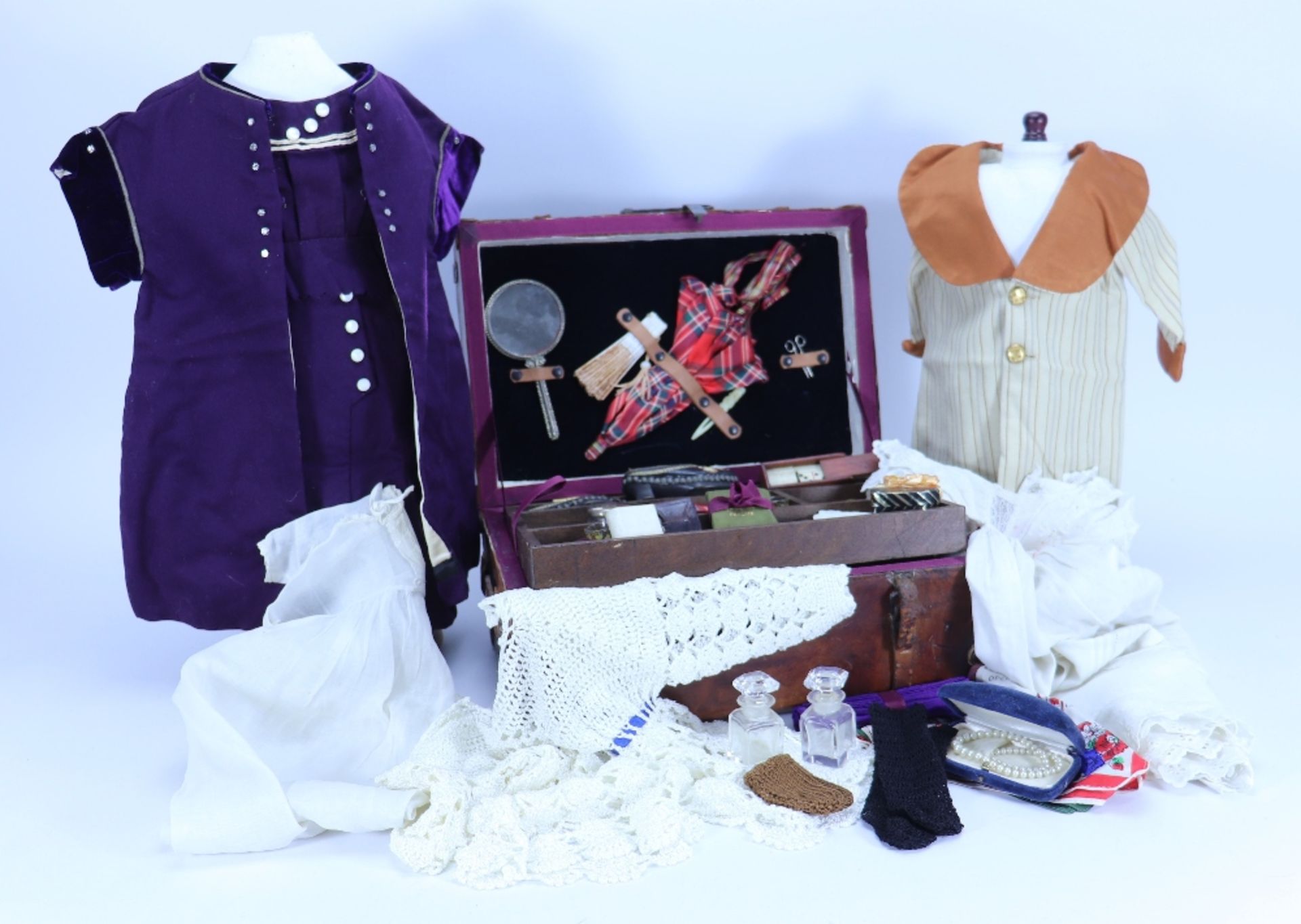 A brown leather dolls trunk with clothes and accessories,