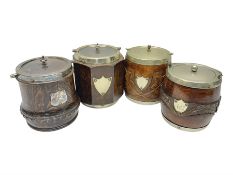 Four early 20th century carved oak biscuit barrels with silver-plated mounts