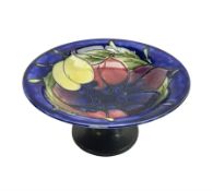 Moorcroft small pedestal dish decorated in the Wisteria pattern against a dark blue ground raised to