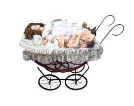 Three porcelain dolls and a wicker dolls pram with lace cover