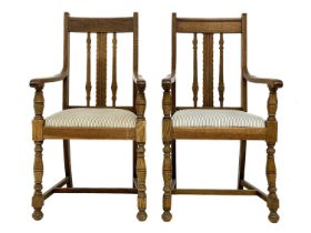 A pair of Arts and Crafts oak armchairs.