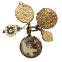 A selection of four gold charms and a rolled gold frame glazed panel locket.