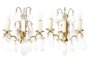 A pair of brass and cut glass triple wall lights.