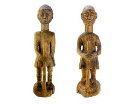 A pair of African carved wood figures of soldiers holding rifles, on circular bases.
