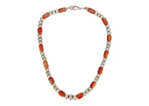 A Christine Povey necklace with orange beads interspaced between three hammered silver beads, the