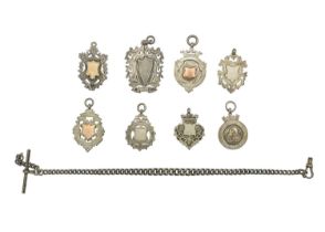 A selection of eight silver shield watch fobs and a silver Albert watch chain.