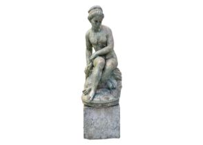 A green painted garden statue of a seated female nude.