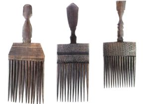 Three African carved hardwood combs, each with a carved mask handle.