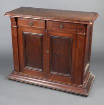 A Victorian oak cabinet fitted 2 drawers above a double cupboard enclosed by a pair of panelled