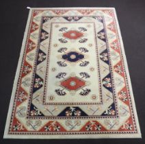 A Caucasian style white and blue ground machine made rug with 3 diamonds to the centre within a