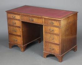 A mahogany kneehole desk with red inset writing surface above 1 long and 8 short drawers, raised