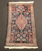A Persian red and blue ground rug with central medallion 146cm x 79cmIn wear, signs of flecking in