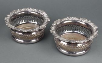 A pair of silver plated pierced wine coasters with scroll decoration