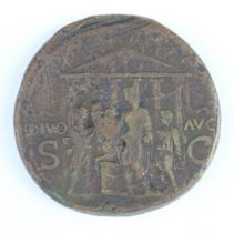 A Roman brass sestertius coin for Caligula, 40-41AD, one side shows Pietas seated with her elbow