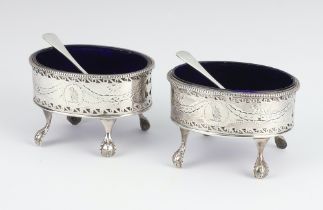 A pair of Georgian oval silver pierced salts with blue glass liners and later spoons, maker Hester
