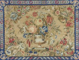 A Victorian wool work embroidery of a still life vase of flowers enclosed in a geometric border