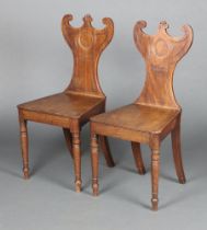 A pair of Georgian mahogany shaped hall chairs with crescent shaped backs, solid seats, raised on