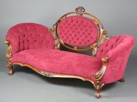 A Victorian carved walnut show frame sofa the back upholstered in red buttoned material raised on