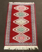 A Bokhara red, pink and turquoise ground rug with 5 diamonds to the centre 152cm x 97cm Fringe