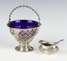 An Edwardian pierced repousse silver basket with swing handle and a blue glass liner Chester 1904,