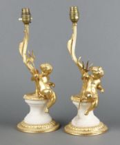 Two gilt metal marble effect table lamps supported by cherubs on circular bases 38cm h The cherubs