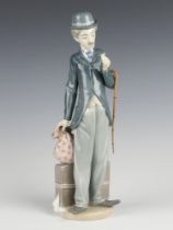 A Lladro figure of a standing Charlie Chaplin with suitcase sack and walking cane, 28cm