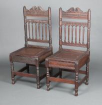 A pair of 17th Century style carved oak hall chairs with spindle turned backs and solid seats,
