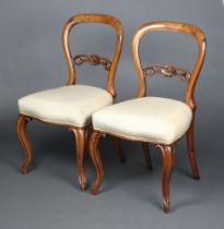 A pair of Victorian carved and pierced walnut ballon back dining chairs with overstuffed seats,