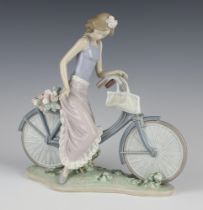 A Lladro figure of a lady on a bicycle 25cm