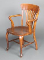An Edwardian beech framed stick and rail back open arm office chair with solid seat, raised on