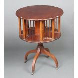 An Edwardian circular mahogany revolving bookcase, raised on a turned column and tripod base with