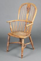A 19th Century elm Windsor comb back carver chair with solid seat and crinoline stretcher, raised on