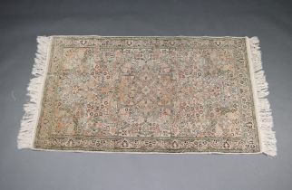 A pink and green ground Persian rug with rectangular floral patterned medallion to the centre