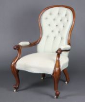A Victorian mahogany show frame armchair upholstered in green and gold floral material, raised on