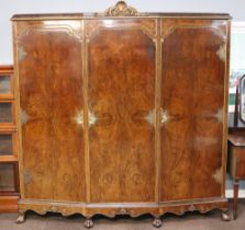 A 1930's Italian style walnut triple wardrobe with carved crest to the centre, the centre fitted 3