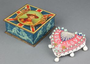 A CAW & Co Ltd biscuit tin, the lid decorated Baiden Powell and containing a heart shaped cushion