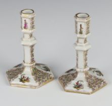 A pair of 19th Century German hexagonal candlesticks decorated with panels of figures and flowers