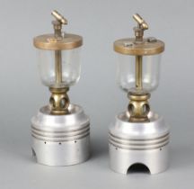 Two aluminium pistons with glass and brass oil reservoirs marked Pat 503444, the base of the pistons