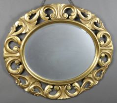 An oval bevelled plate wall mirror contained in a gilt carved wooden frame 66cm x 75cm Light chips