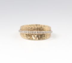 A 9ct two colour gold hammered pattern and diamond set ring, size O, 4.9 gramsThis ring has some