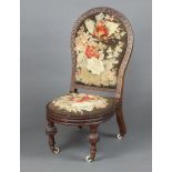 A Victorian carved mahogany show frame nursing chair with Berlin woodwork embroidered back and