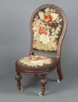 A Victorian carved mahogany show frame nursing chair with Berlin woodwork embroidered back and