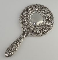 A Victorian style repousse silver backed hand mirror with vacant cartouche, mask and scroll