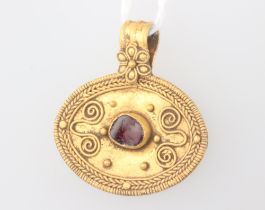 A Roman style oval gold pendant set with a rough cut garnet with Etruscan style decoration 3.5