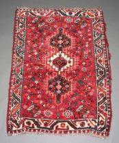 A red, blue and black ground Afghan rug with 3 stylised medallions to the centre 153cm x 107cm In