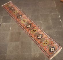 An orange, brown and blue ground Persian runner with 10 stylised medallions to the centre within a