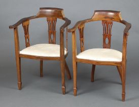 A pair of Edwardian beech framed tub back chairs with splat back decoration, the seats of serpentine