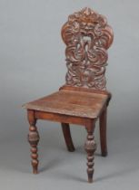 A Victorian oak hall chair, the carved and pierced solid back carved a green man, raised on turned