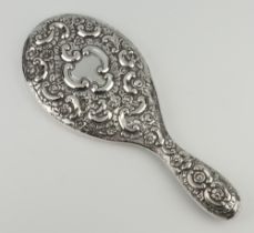 A Victorian repousse silver hand mirror decorated with scrolls and flowers and vacant cartouche