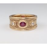 A 9ct yellow gold Etruscan style ring set with an oval cut ruby and 2 brilliant cut diamonds, the